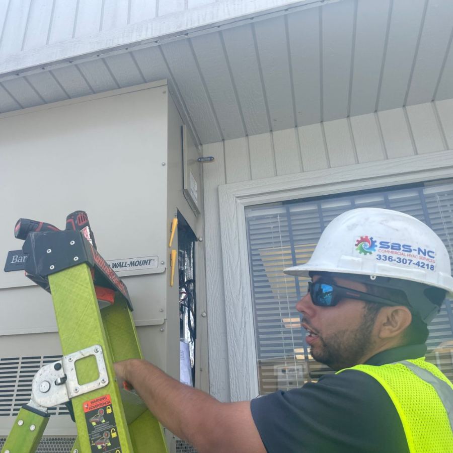 SBS-NC technician installing a commercial wall-mount HVAC unit